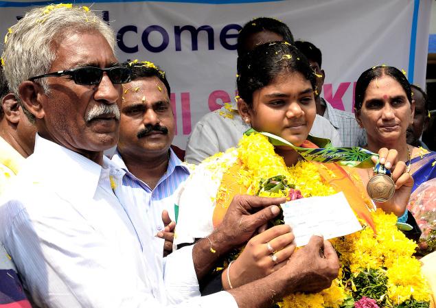 CBR Sports Academy chairman Chalasani Balaramaiah handing over a cheque for Rs. 5 lakh to Asian Games bronze medallist Jyothi Surekha on her arrival at Gannavaram Airport on Saturday. - Photo: Ch.Vijaya Bhaskar